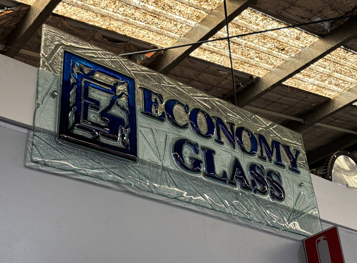 Moulded glass sign featuring a blue logo and text reading Economy Glass