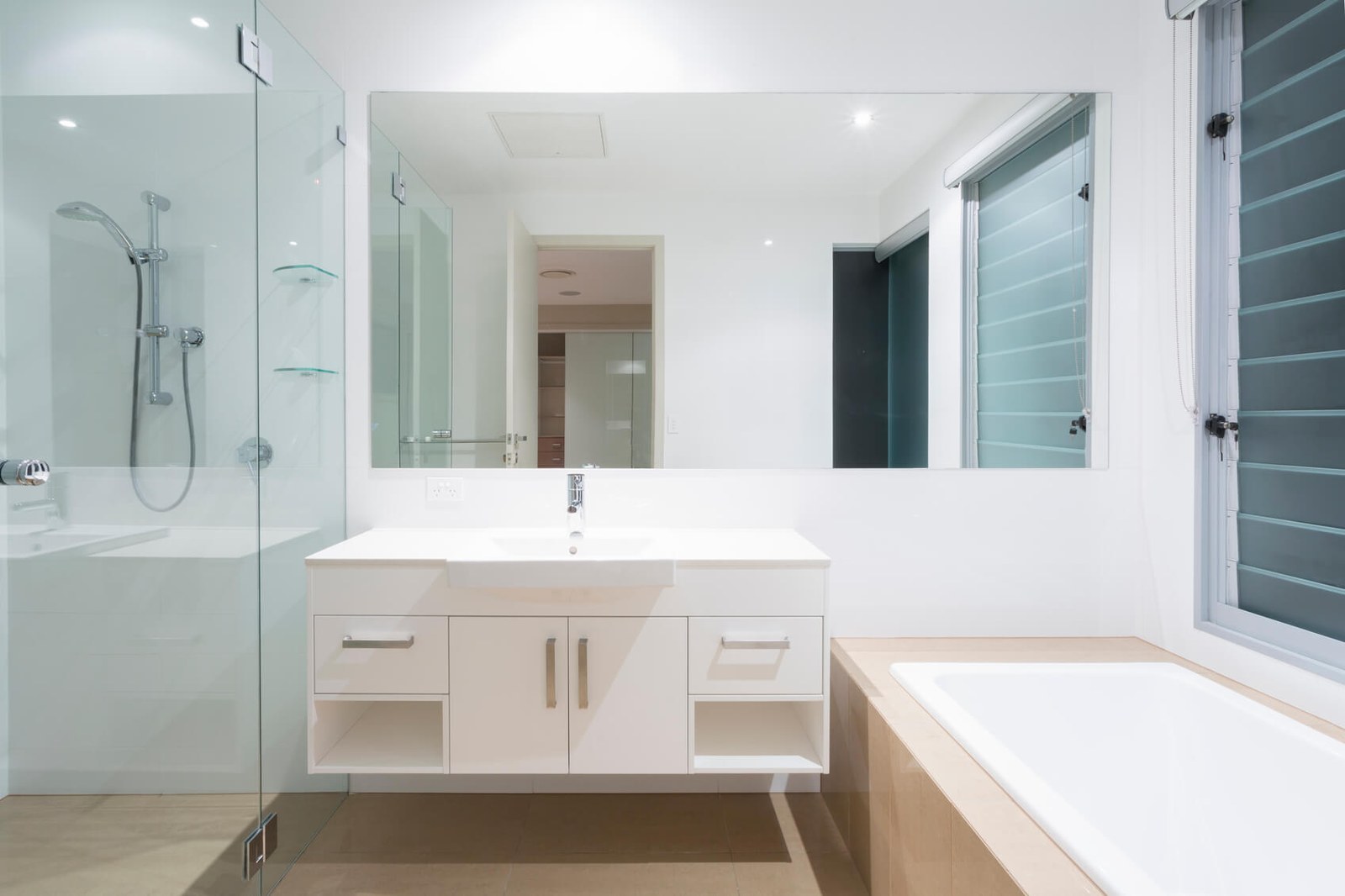 A renovated Melbourne bathroom with a frameless glass shower screen beside a wall-hung vanity and a large mirror