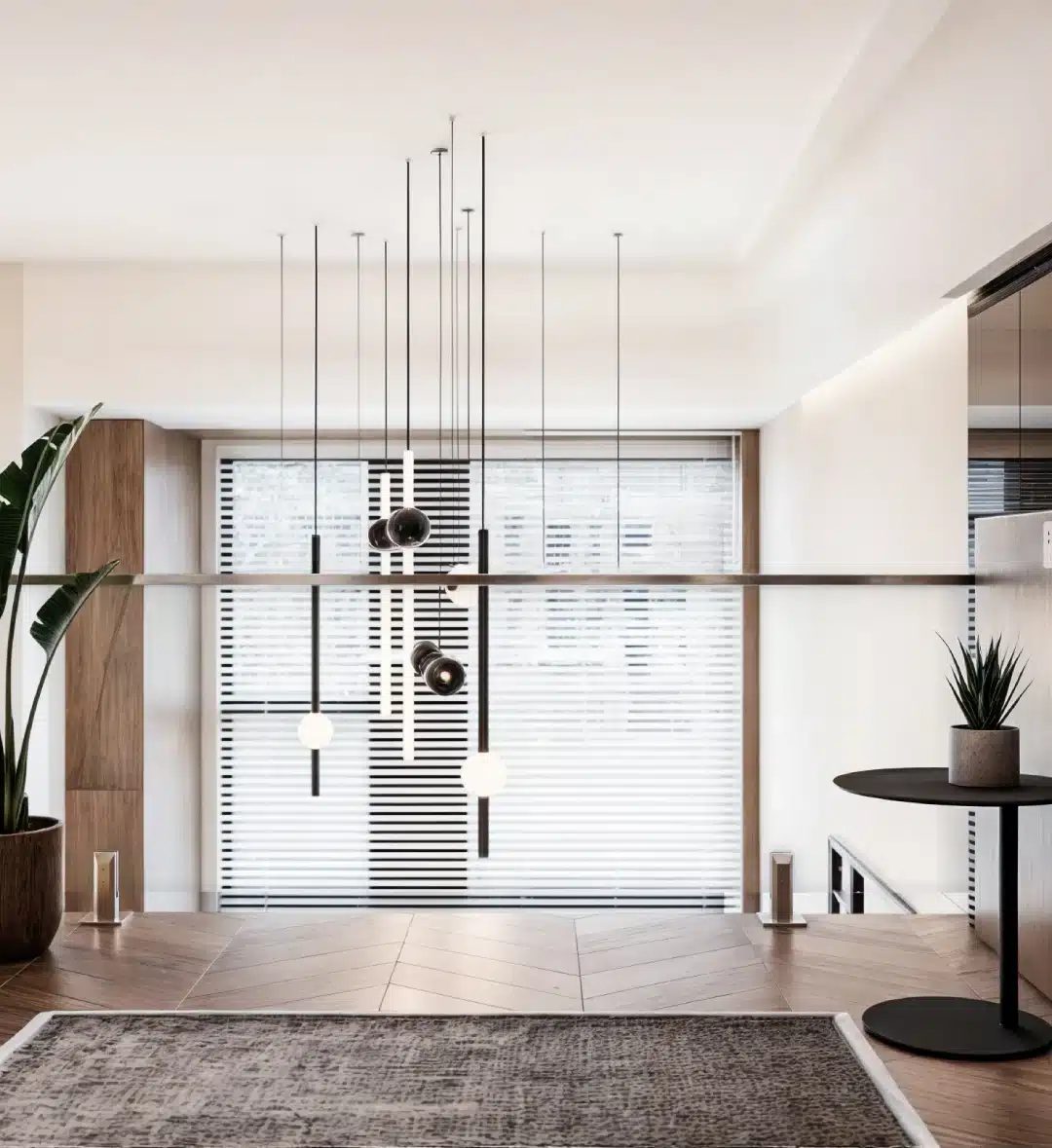 Glass balustrade along a mezzanine edge with a slim metal handrail, looking over a double-height living space with pendant lights