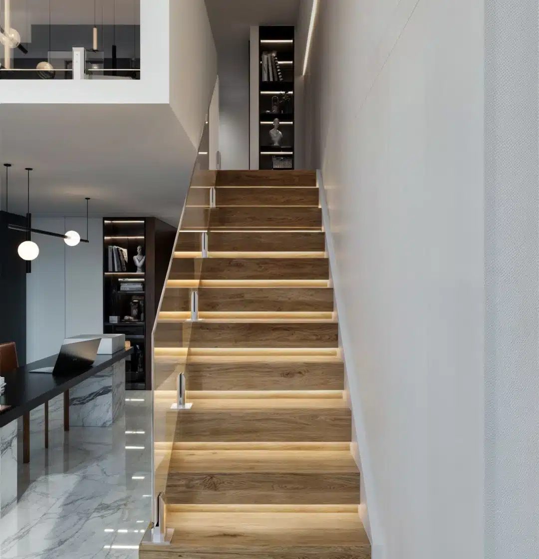 Glass balustrade on stairs: raked clear glass panels held by stainless steel spigots on a timber staircase inside a modern home
